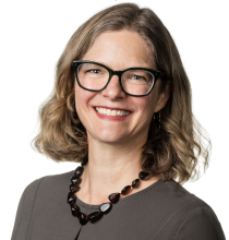 Blair's headshot; she's a White woman with short blonde hair wearing a brown blouse and black glasses